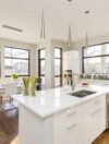 white kitchen island An interior shot of a modern house kitchen with large windows