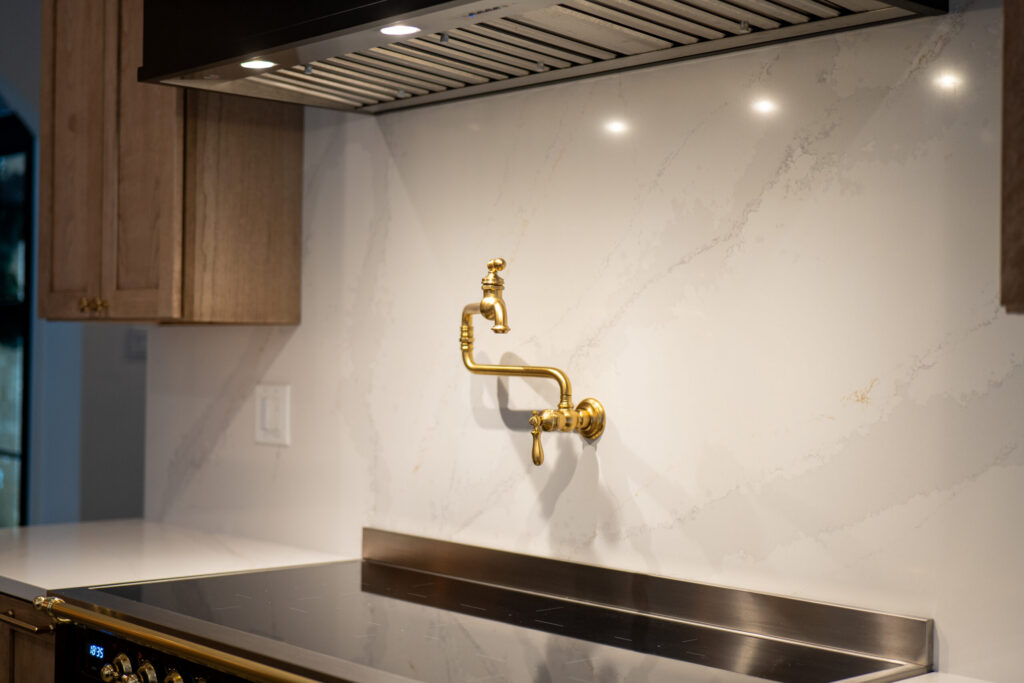 quartz slab kitchen backsplash with brass pot filler and under cabinet lighting in modern kitchen