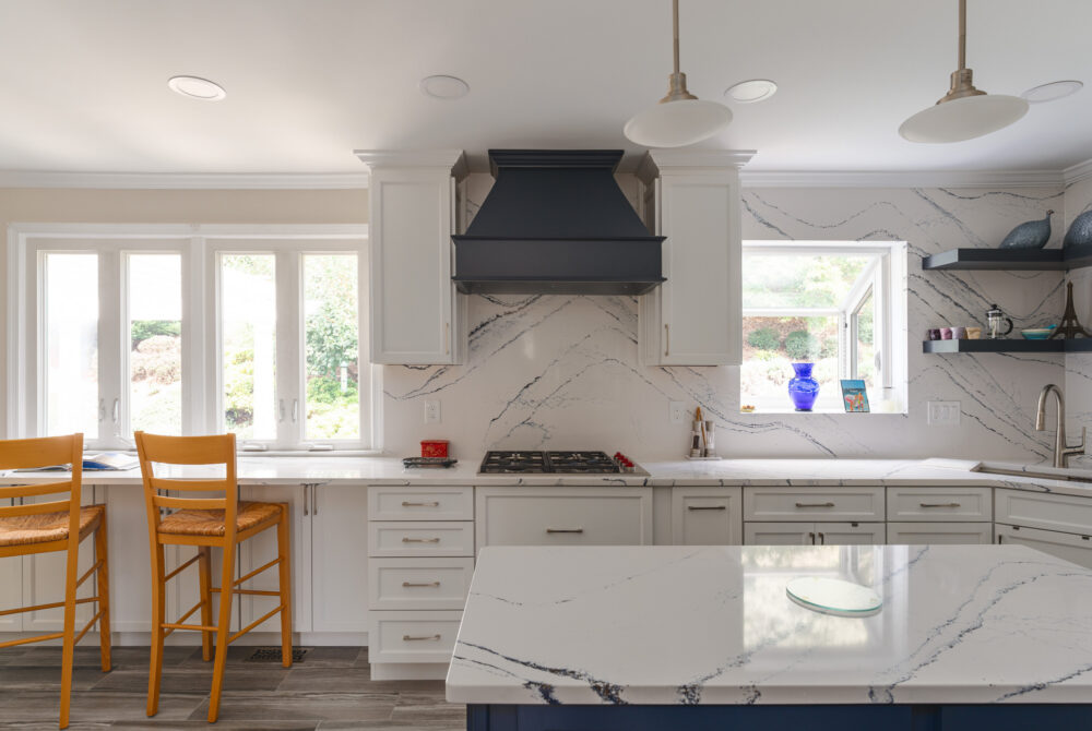 modern kitchen with white quartz countertops and full height veined quartz backsplash behind cooktop
