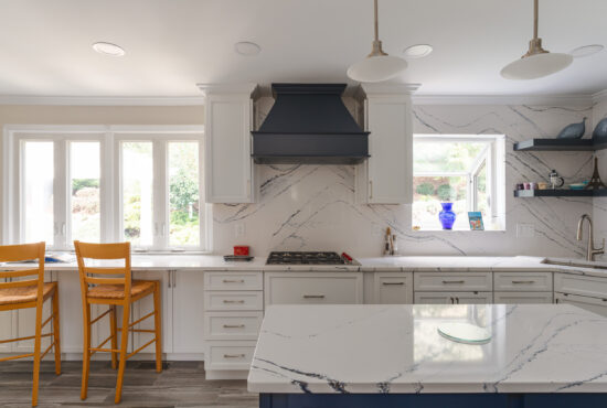 modern kitchen with white quartz countertops and full height veined quartz backsplash behind cooktop
