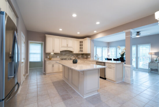 classic white kitchen remodel with large island, quartz countertops, recessed lighting, and open dining area
