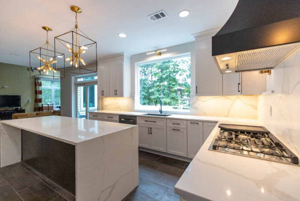 Waterfall kitchen island in an Ashburn, VA kitchen remodel, paired with a black range hood, gold cube chandeliers, and an open-concept layout.