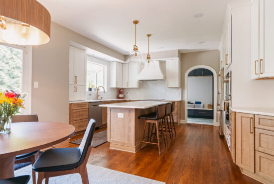 Remodeled kitchen in Vienna, VA, with white upper cabinets, wood lower cabinets, an island, and an adjacent dining area.